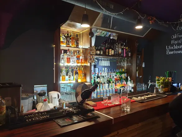 The bar at Maracas: wooden counter, bottles lit from behind